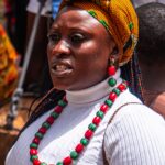 Portrait of a woman in traditional attire with colorful beads and a head wrap, showcasing cultural heritage.