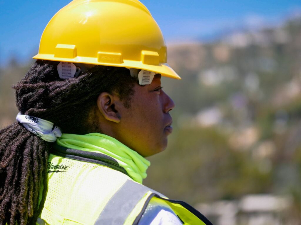 Professional female engineer wearing safety gear and hardhat at a construction site outdoors.